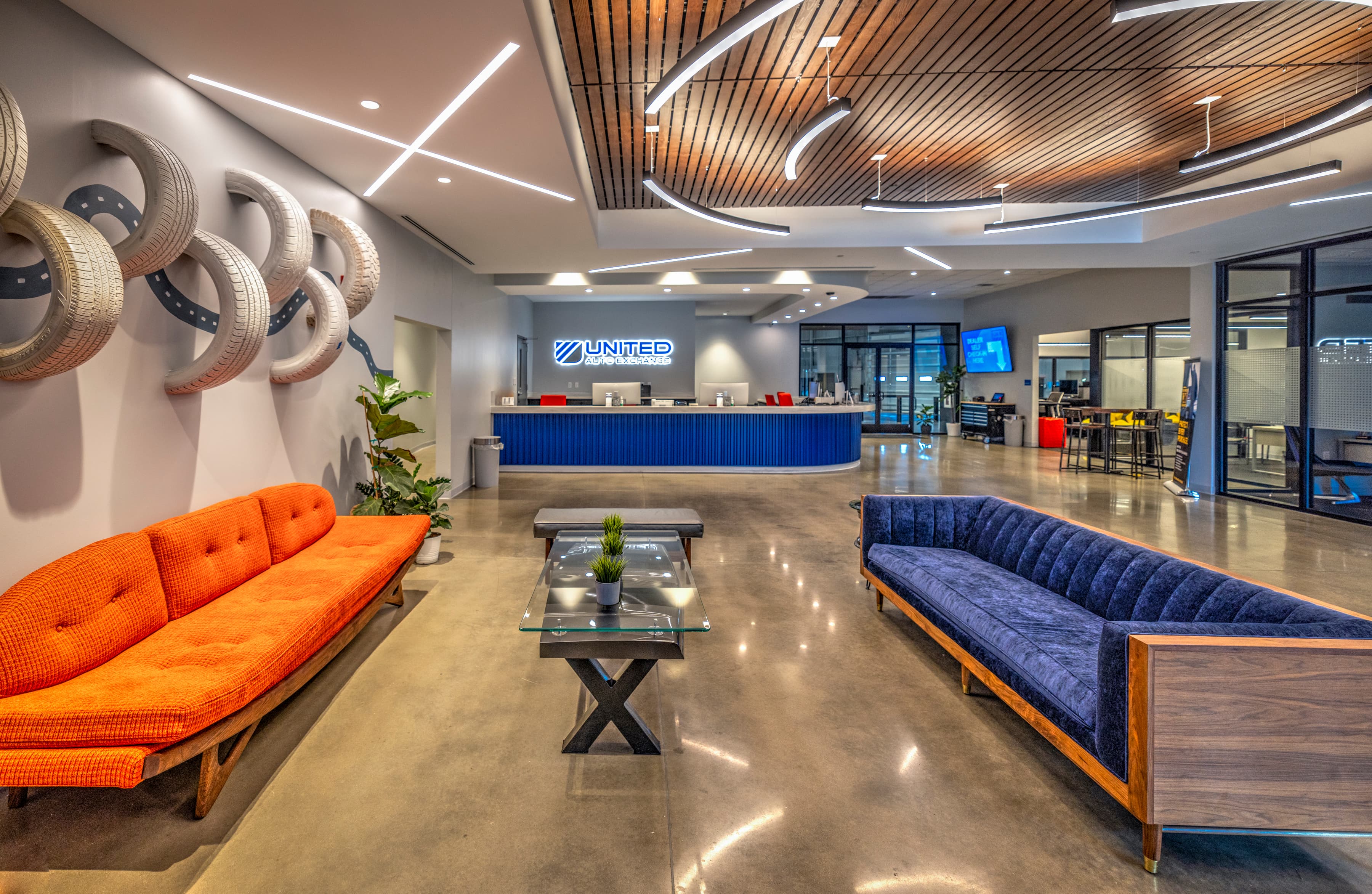 The UAX lobby, tire wall sculpture, orange and navy seating, wood-slat ceiling